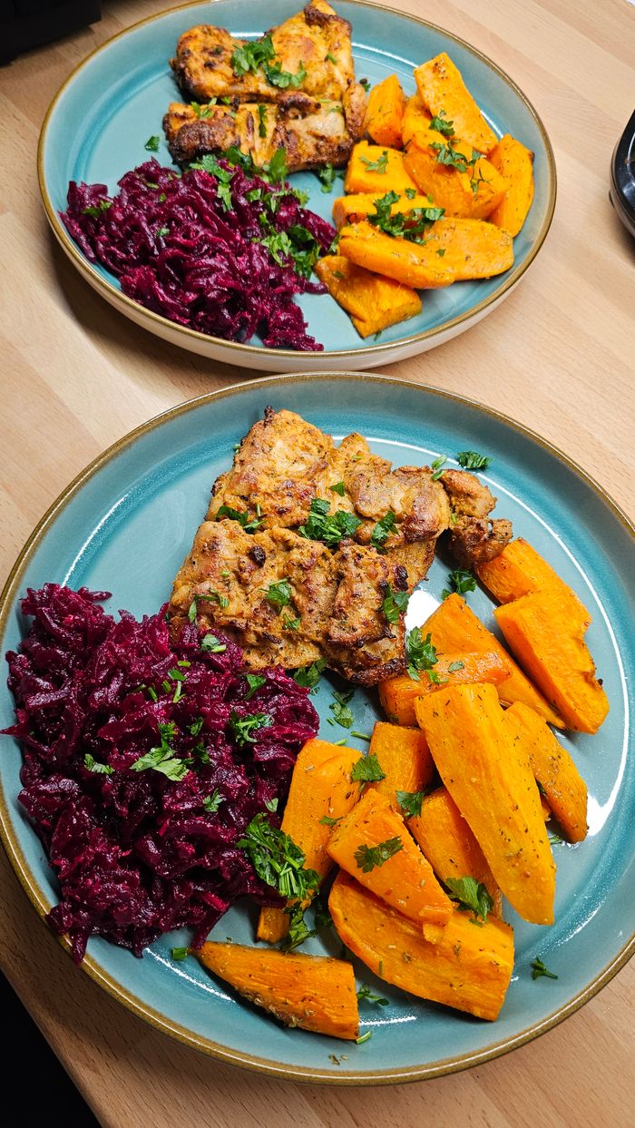 Colorful chicken and vegetable dish with sweet potatoes and beetroot on blue plates. Perfect for food blogs and healthy eating themes.